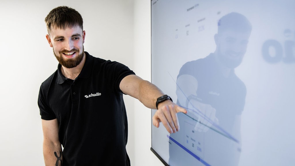 A Schudio team member reviewing a school website dashboard on a large wall screen