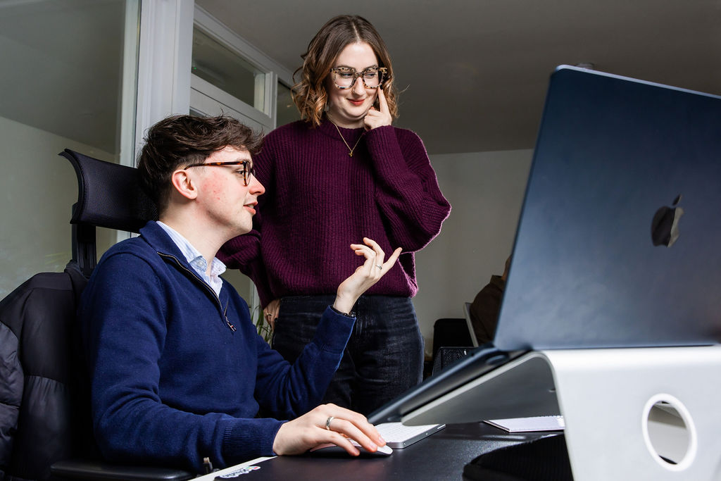 Two Schudio colleagues at a desk talking through a school website compliance question