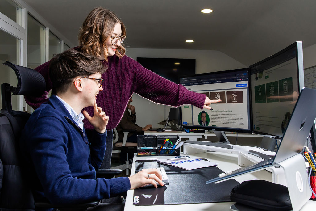 Two Schudio team members looking at a school website page open in the Schudio CMS