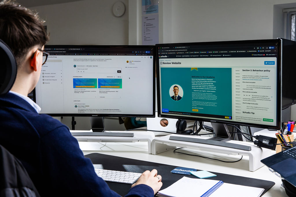 Dual monitors showing the Schudio CMS alongside a live school website policy page
