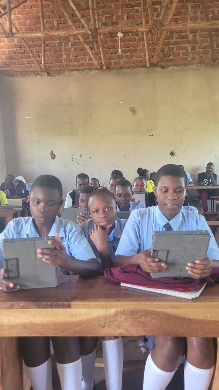 A full classroom at Kingstone Secondary School in Uganda with students reading on iPads at their desks