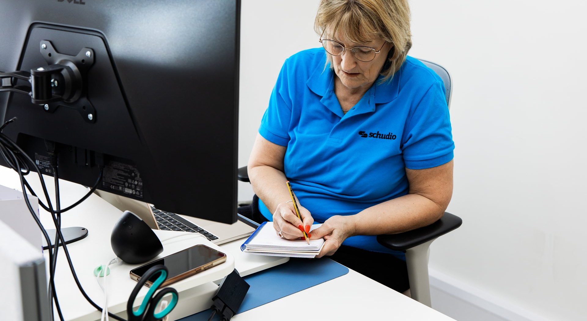 A Schudio team member checking a draft by hand and making notes at her desk