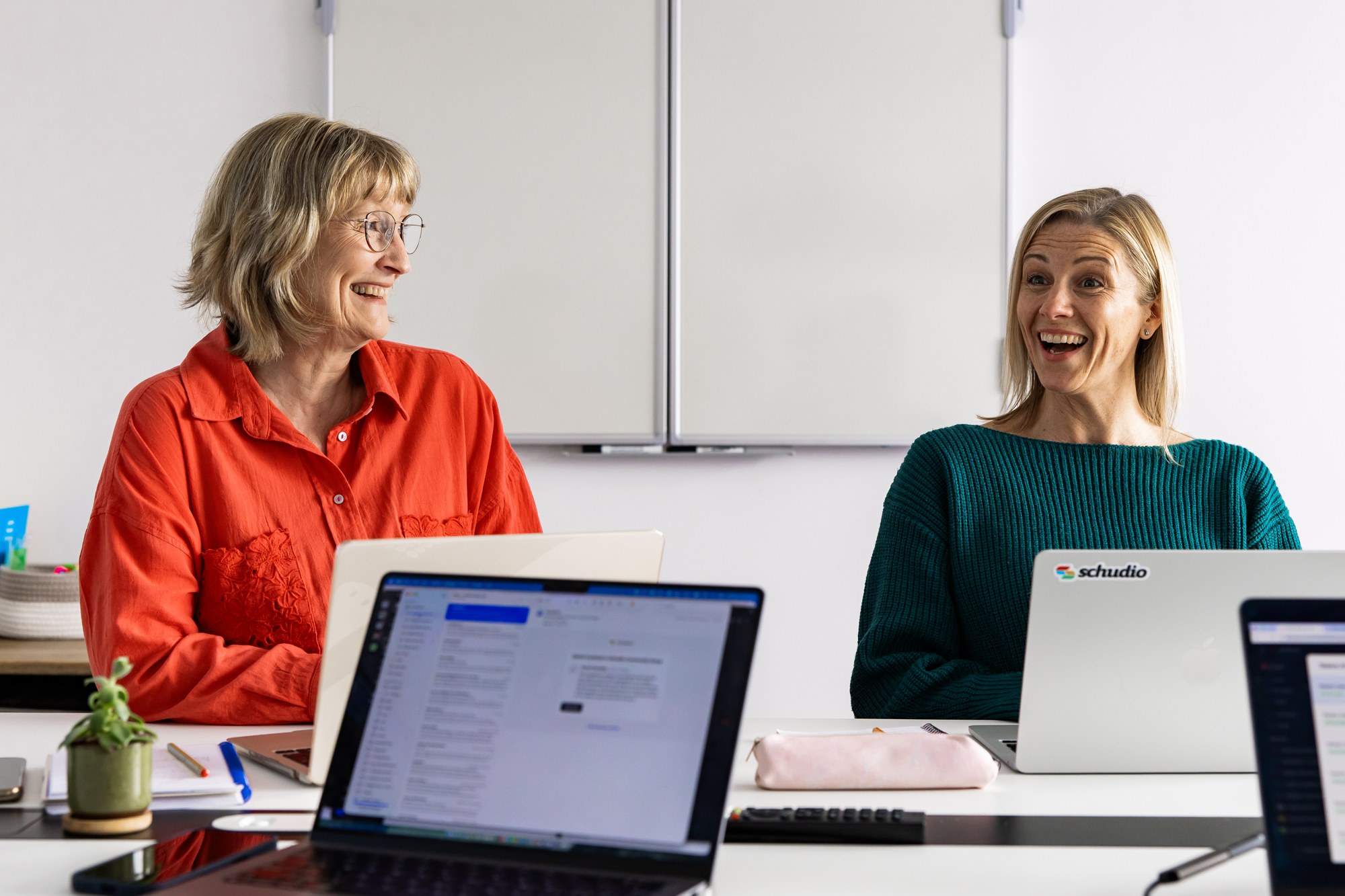 Schudio team members at a meeting table with laptops, working through school website compliance