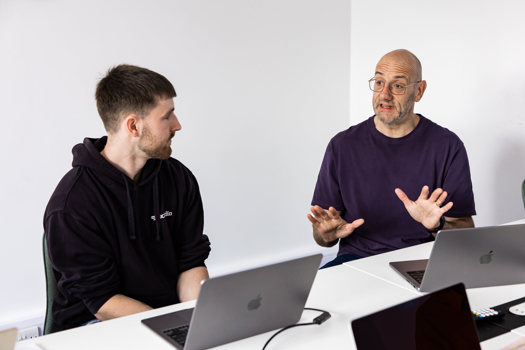 Two Schudio colleagues at their laptops discussing how a school publishes its documents online