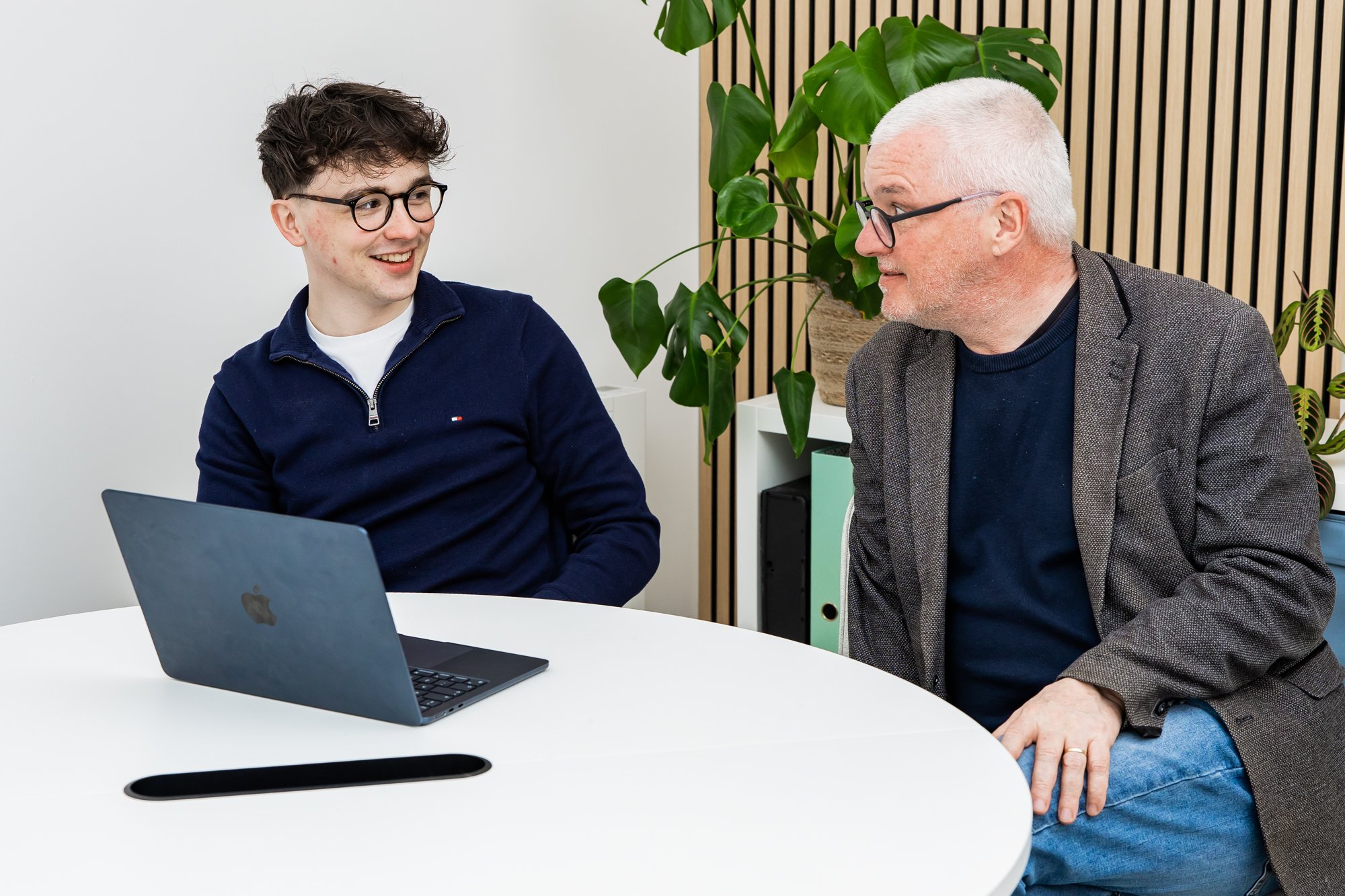 Two Schudio team members talking through school website plans beside a laptop