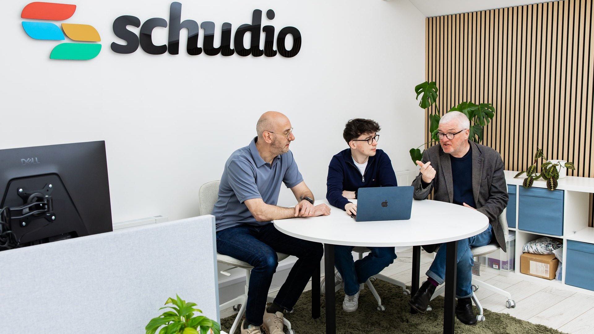 Three members of the Schudio team reviewing website content together on a laptop in the Schudio office