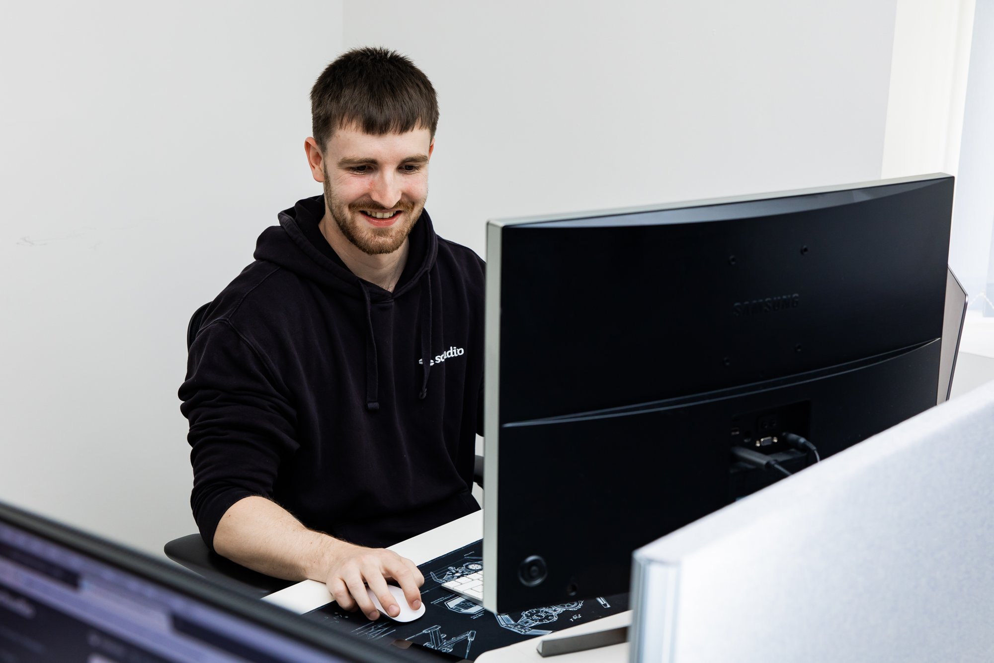 A Schudio team member at his desk building a school web page on a large monitor